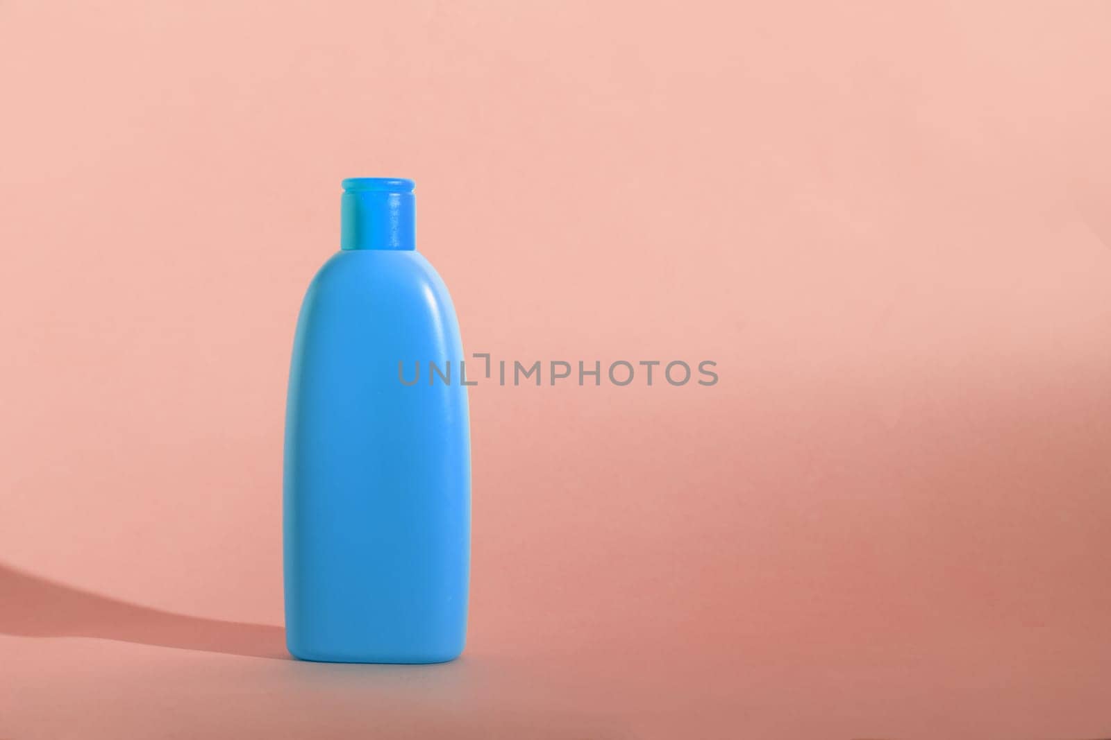 Mock up of a blue bottle with cosmetics product on a pink background. Copy space, pastel colors