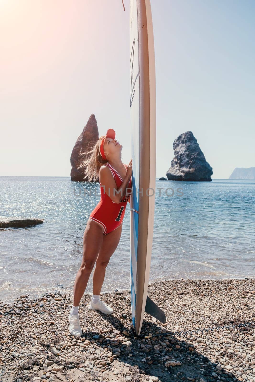 Close up shot of beautiful young caucasian woman with black hair and freckles looking at camera and smiling. Cute woman portrait in a pink bikini posing on a volcanic rock high above the sea