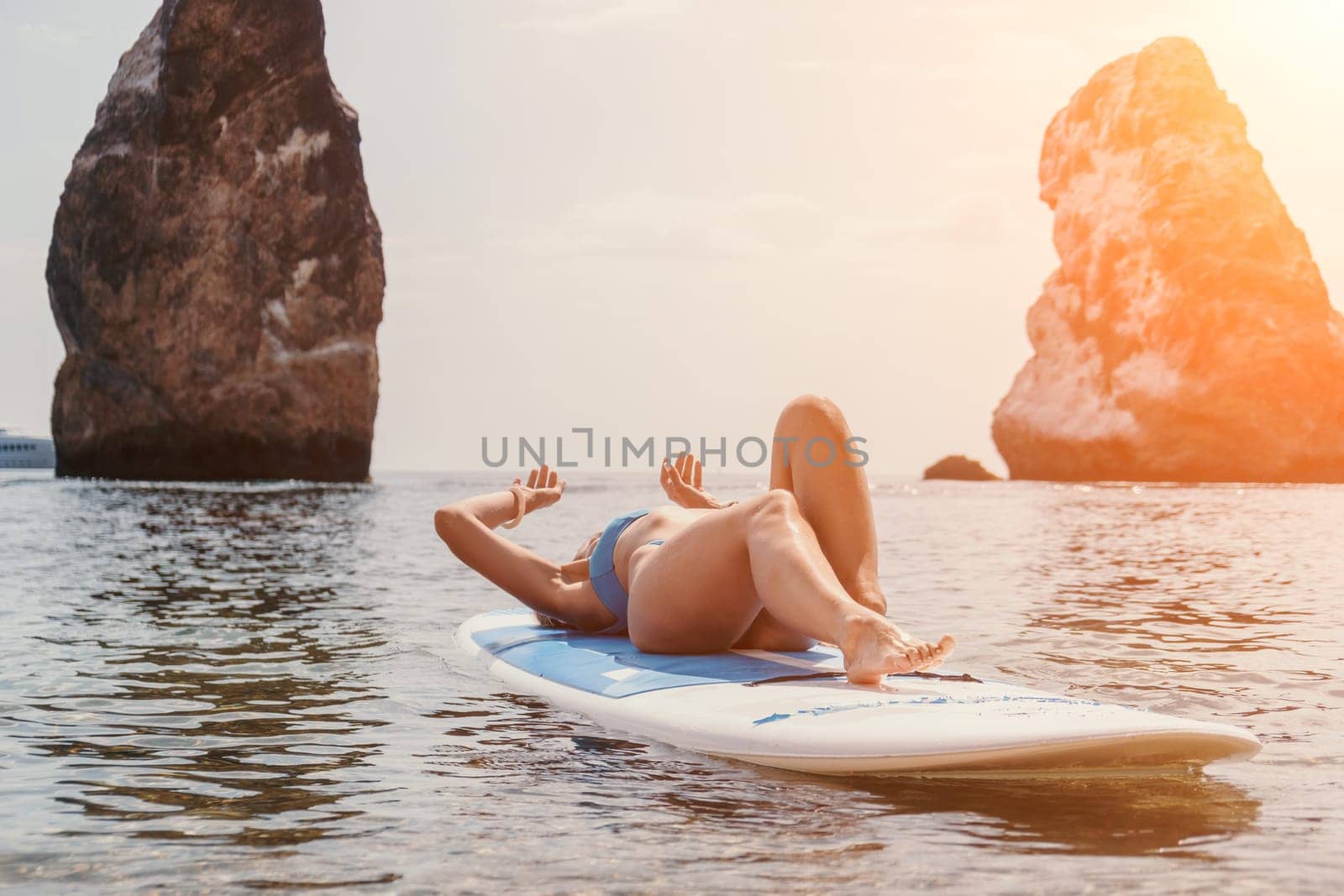 Close up shot of beautiful young caucasian woman with black hair and freckles looking at camera and smiling. Cute woman portrait in a pink bikini posing on a volcanic rock high above the sea