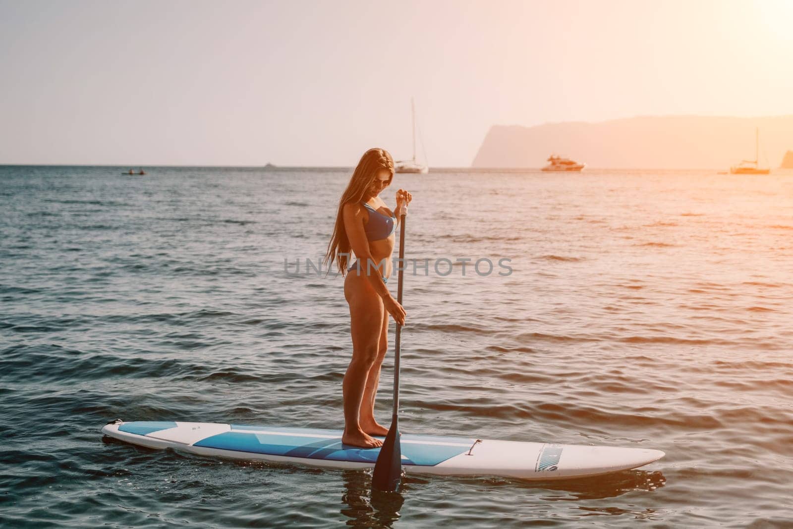 Close up shot of happy young caucasian woman looking at camera and smiling. Cute woman portrait in bikini posing on a volcanic rock high above the sea