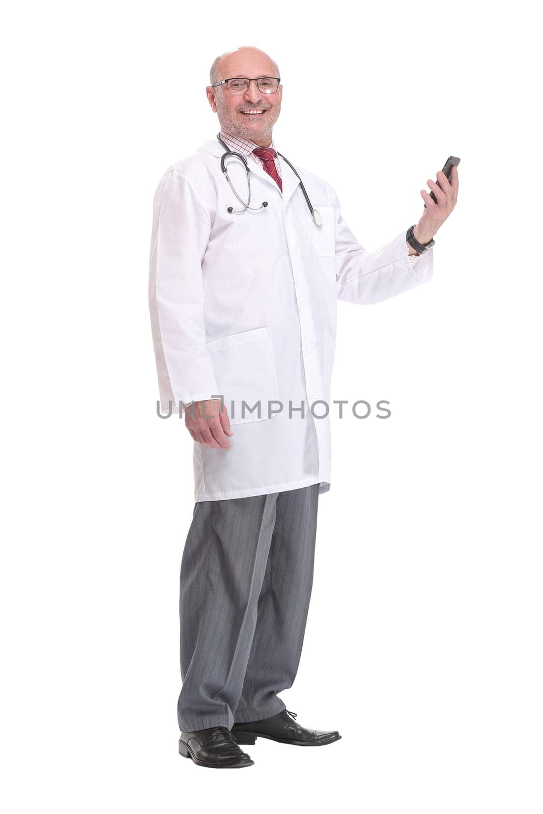Portrait of happy senior smiling doctor holding smartphone. White isolated background.