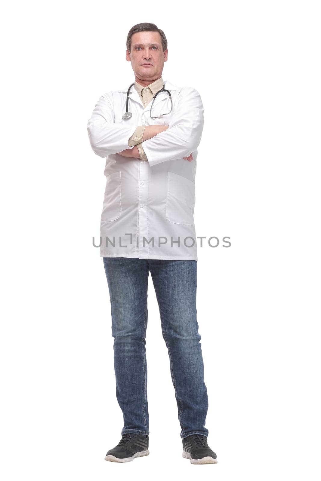 Serious male doctor in scrubs with a stethoscope around his neck and his arms crossed isolated on white background