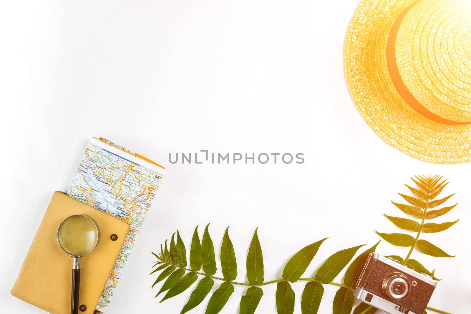 Straw hat with green leaves and old camera on white background, Summer background. Top view. Sun flare by nazarovsergey