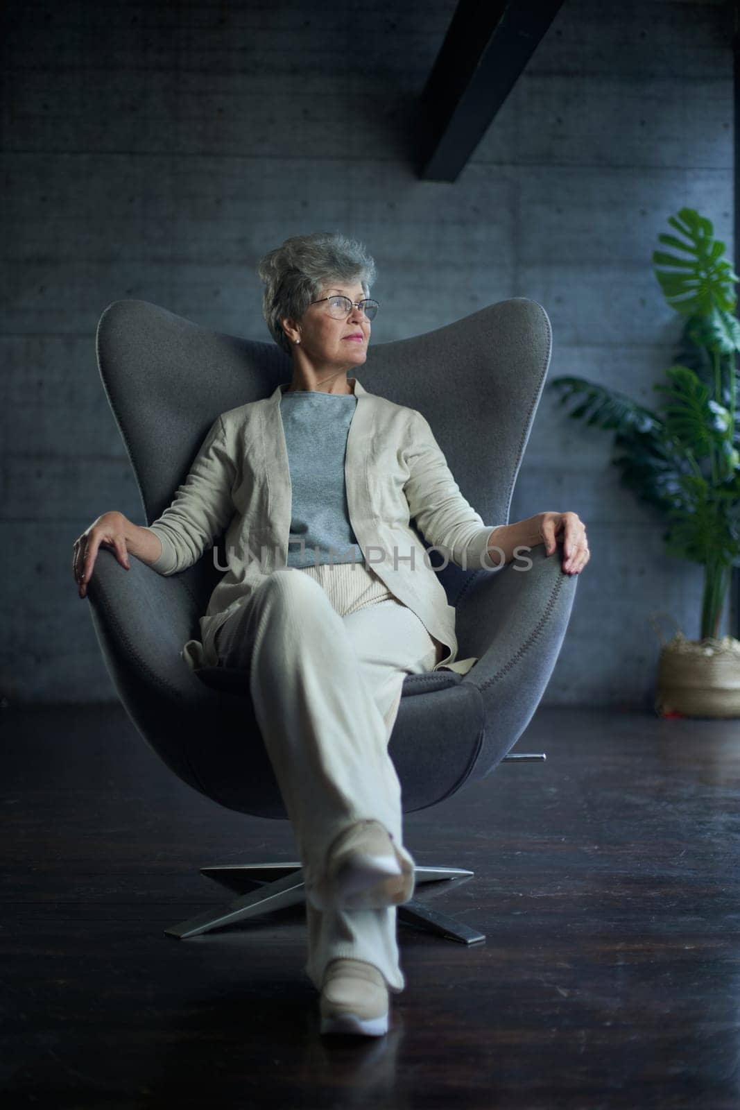 attractive middle aged smiling woman model sitting in chair looking at camera at office