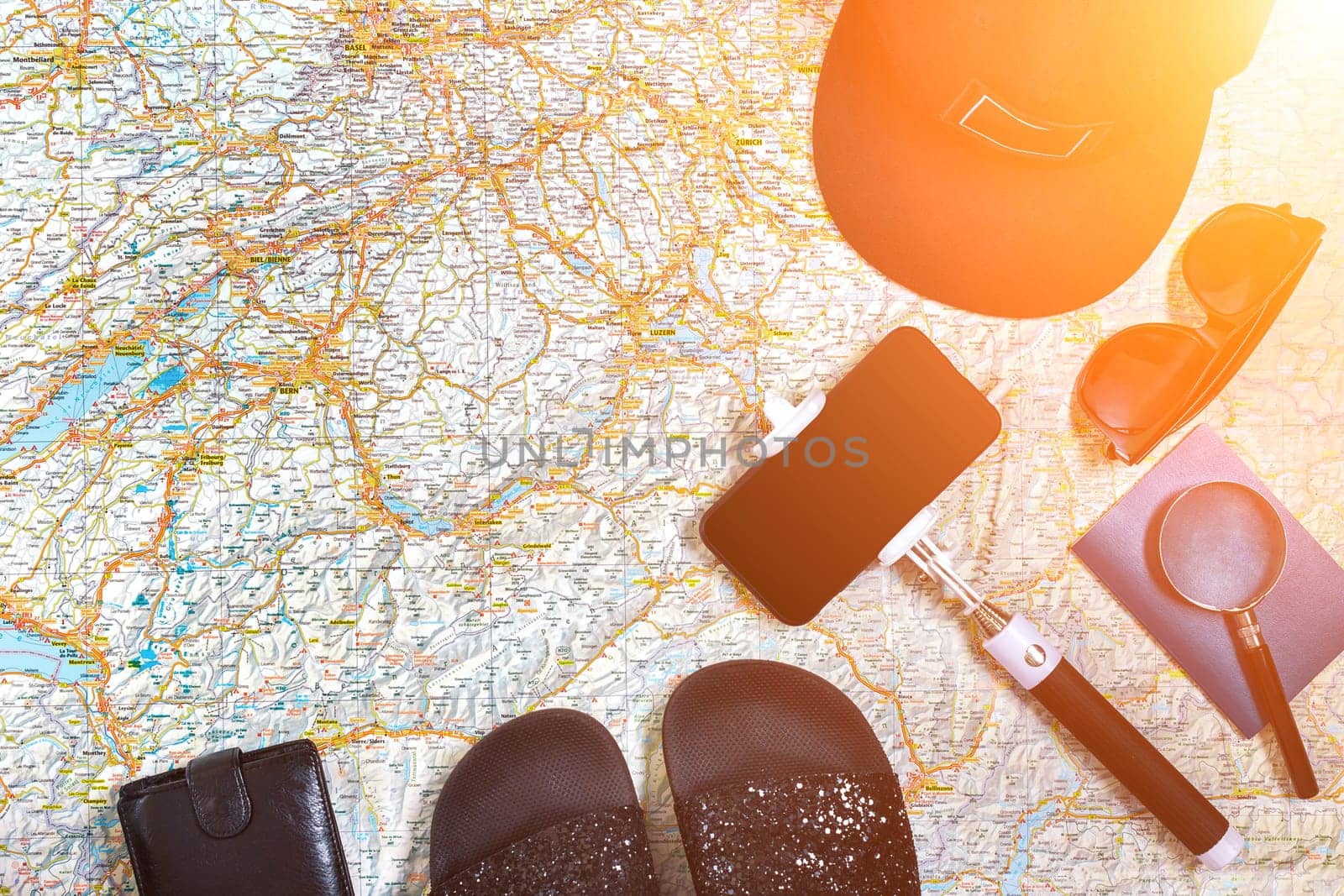 Accessories for travel. Passport, cap, smart phone and travel map. Top view. Holidays and tourism concept. Copy space. Still life. Flat lay. Sun flare