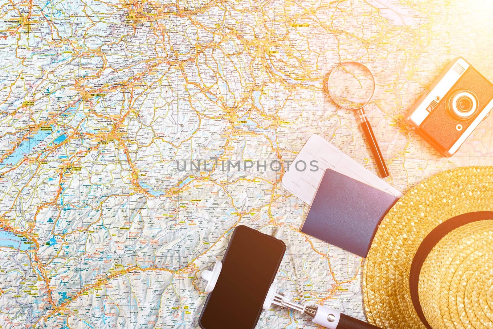 Accessories for travel. Passport, photo camera, smart phone and travel map. Top view. Holidays and tourism concept. Copy space. Still life. Flat lay. Sun flare