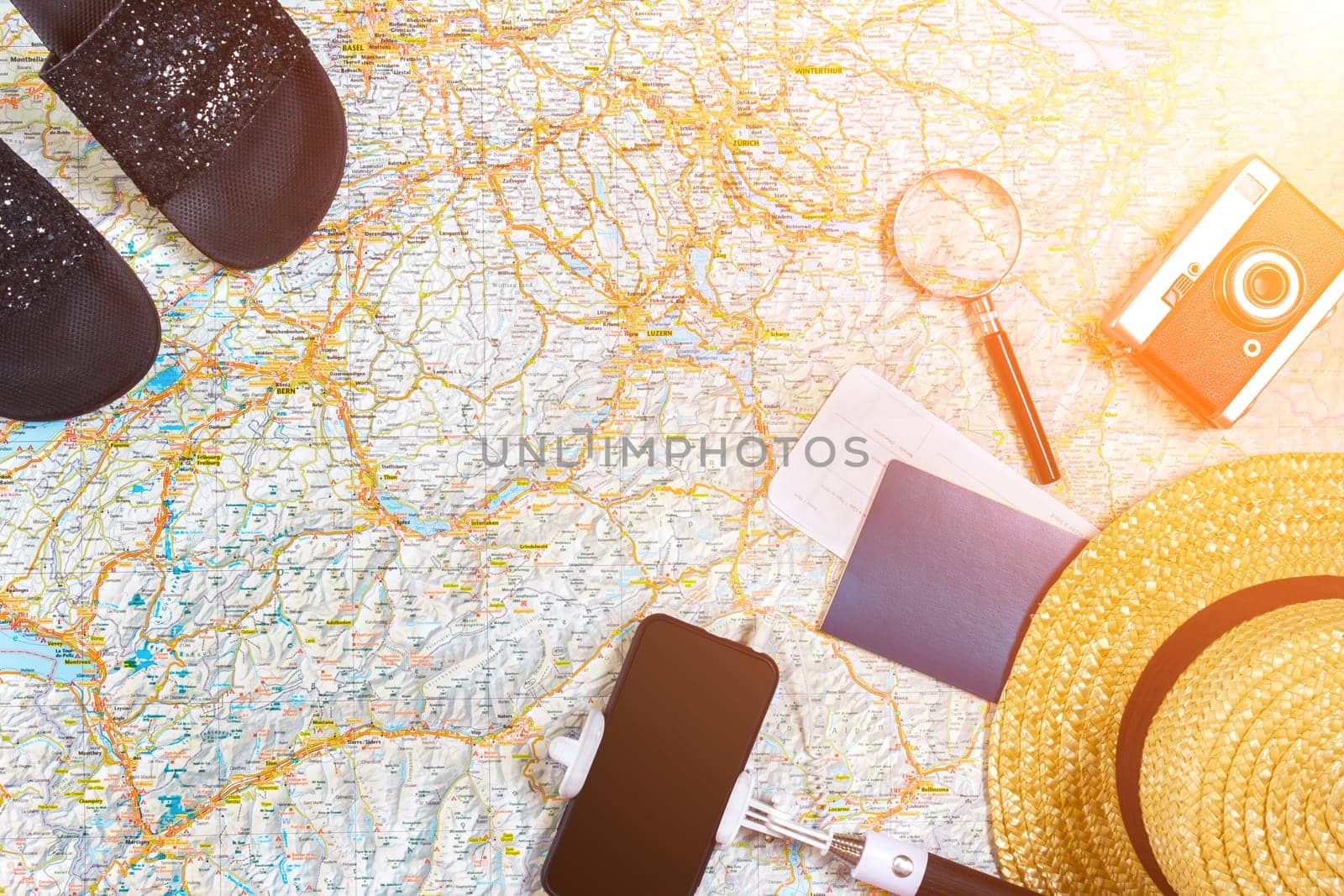 Accessories for travel. Passport, photo camera, smart phone and travel map. Top view. Holidays and tourism concept. Copy space. Still life. Flat lay. Sun flare