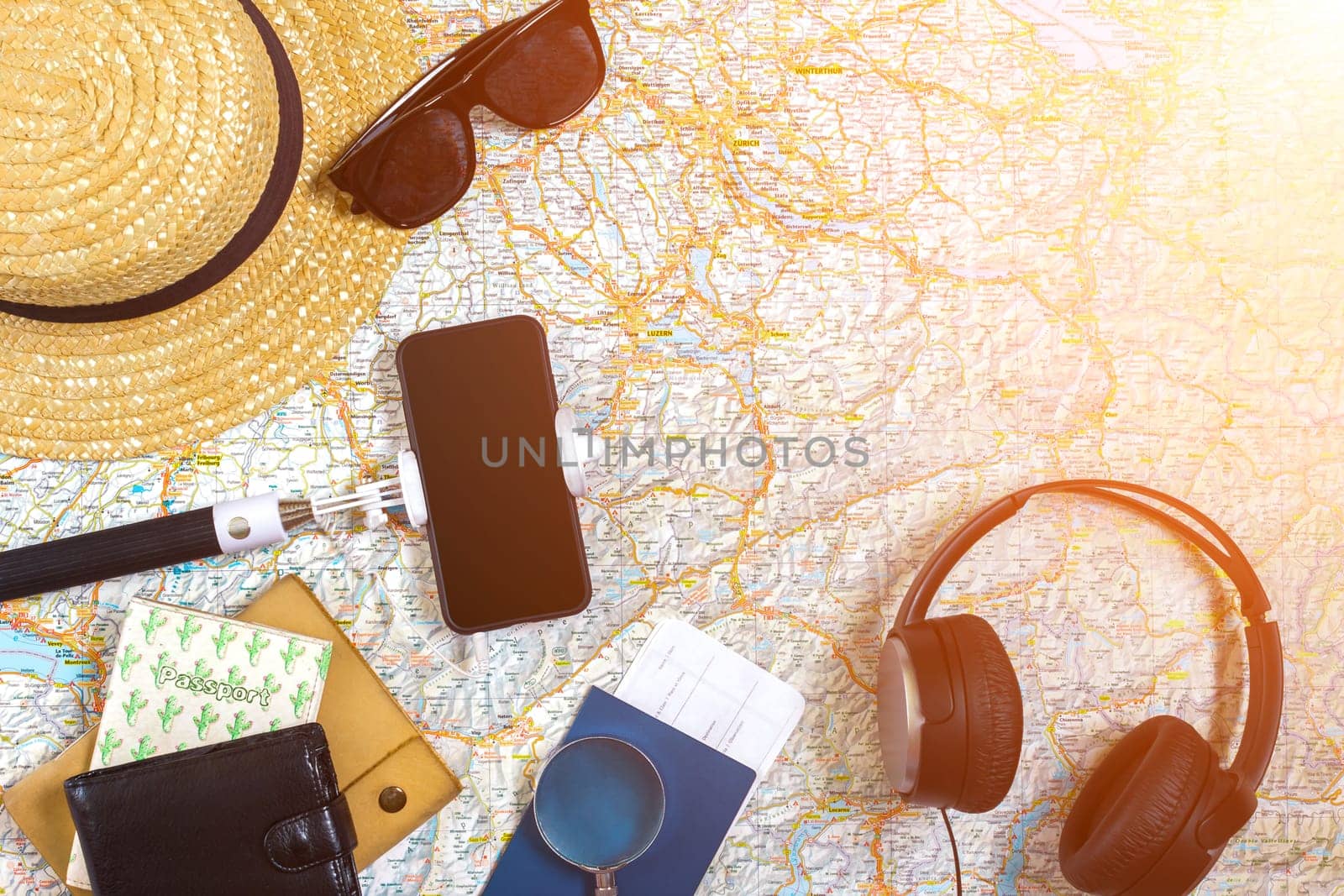 Accessories for travel. Passport, hat, smart phone and travel map. Top view. Holidays and tourism concept. Copy space. Still life. Flat lay. Sun flare