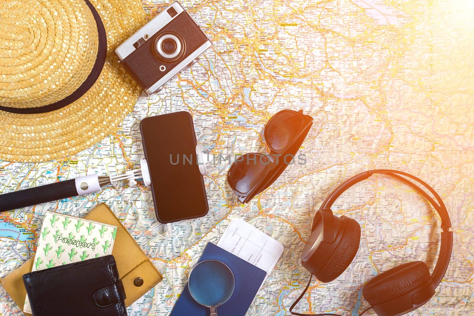 Accessories for travel. Passport, hat, smart phone and travel map. Top view. Holidays and tourism concept. Copy space. Still life. Flat lay. Sun flare