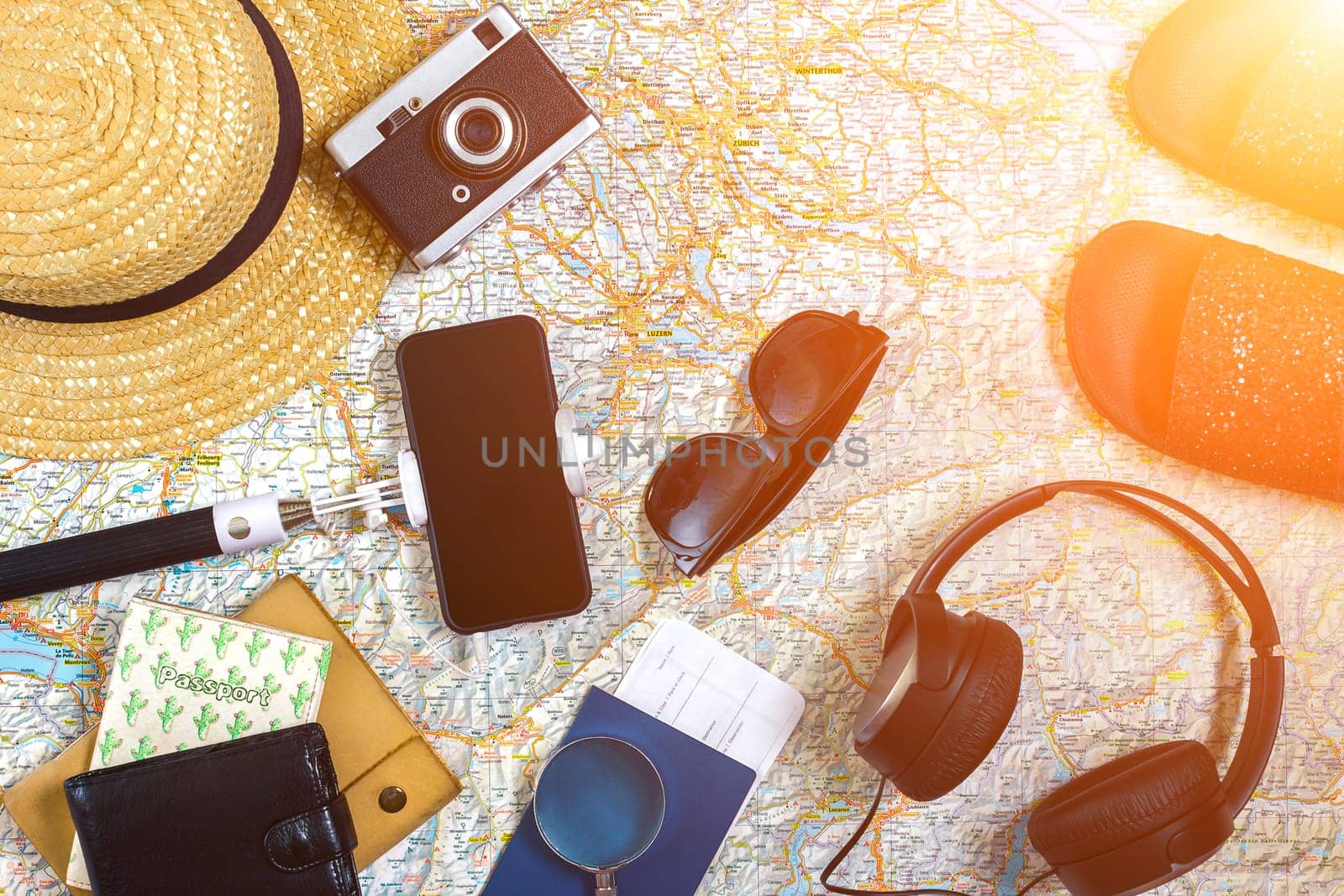 Accessories for travel. Passport, photo camera, smart phone and travel map. Top view. Holidays and tourism concept. Copy space. Still life. Flat lay. Sun flare