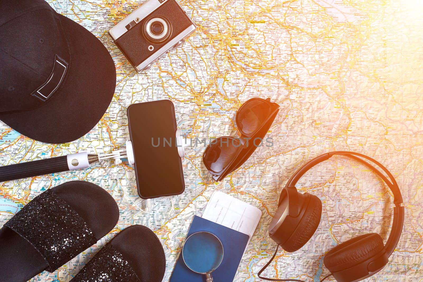 Accessories for travel. Passport, photo camera, smart phone and travel map. Top view. Holidays and tourism concept. Copy space. Still life. Flat lay. Sun flare