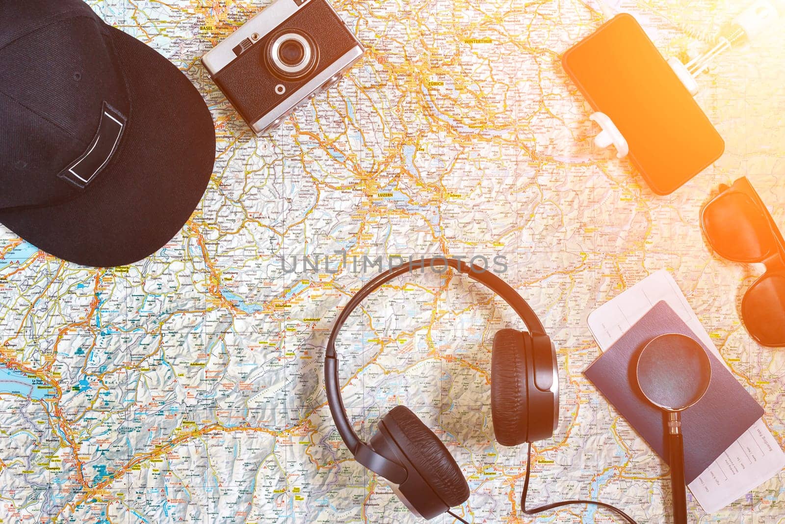 Accessories for travel. Passport, photo camera, smart phone and travel map. Top view. Holidays and tourism concept. Copy space. Still life. Flat lay. Sun flare