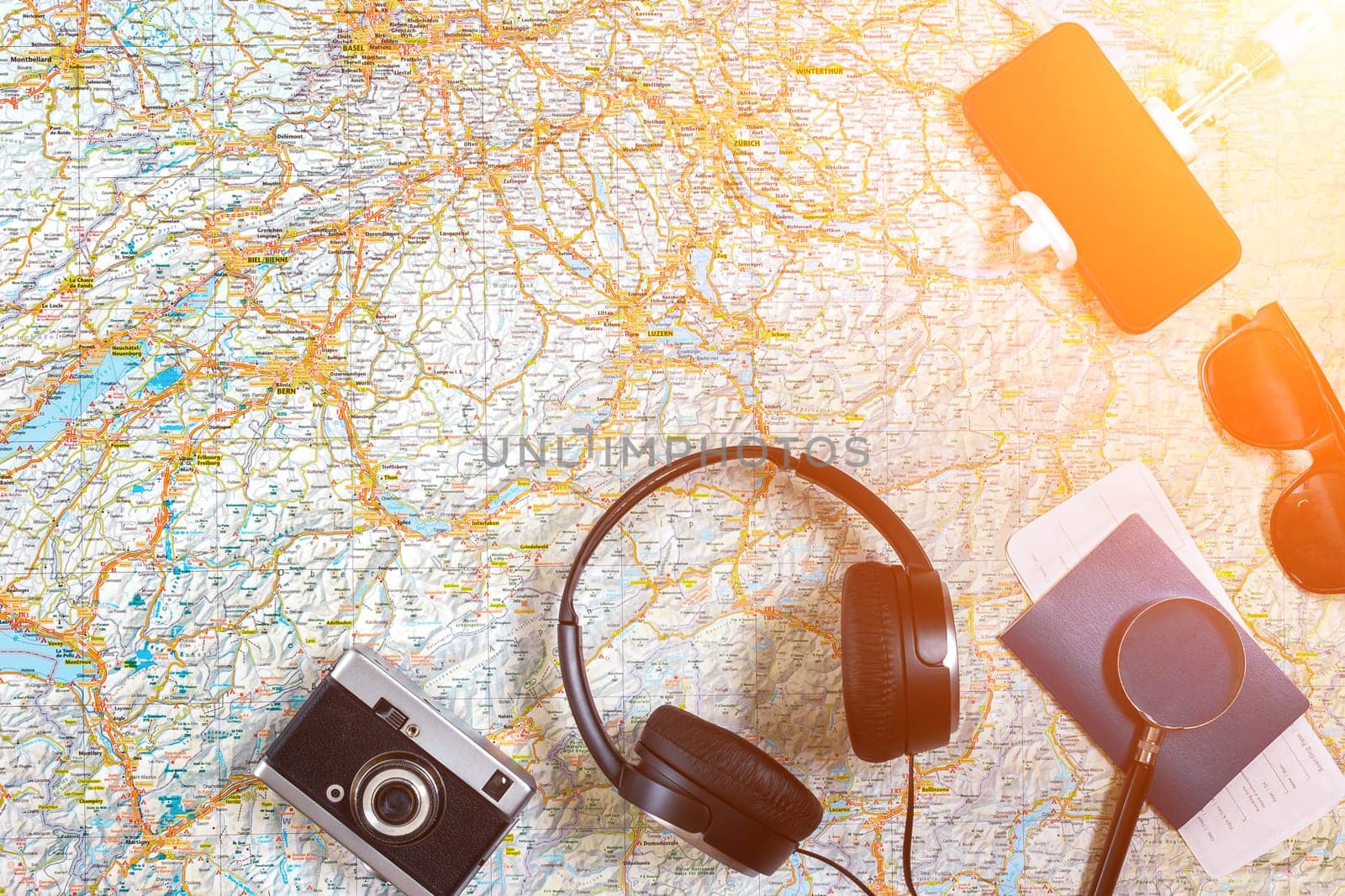 Accessories for travel. Passport, photo camera, smart phone and travel map. Top view. Holidays and tourism concept. Copy space. Still life. Flat lay. Sun flare