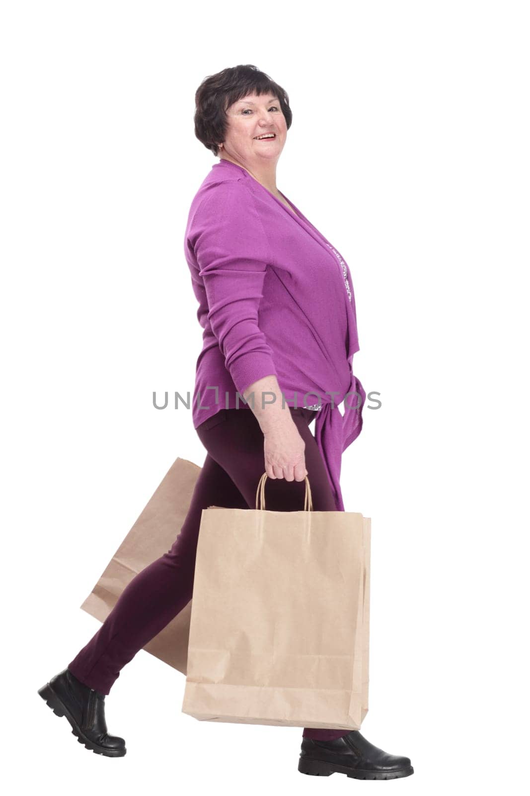 casual elderly woman with shopping bags striding forward. isolated on a white background.