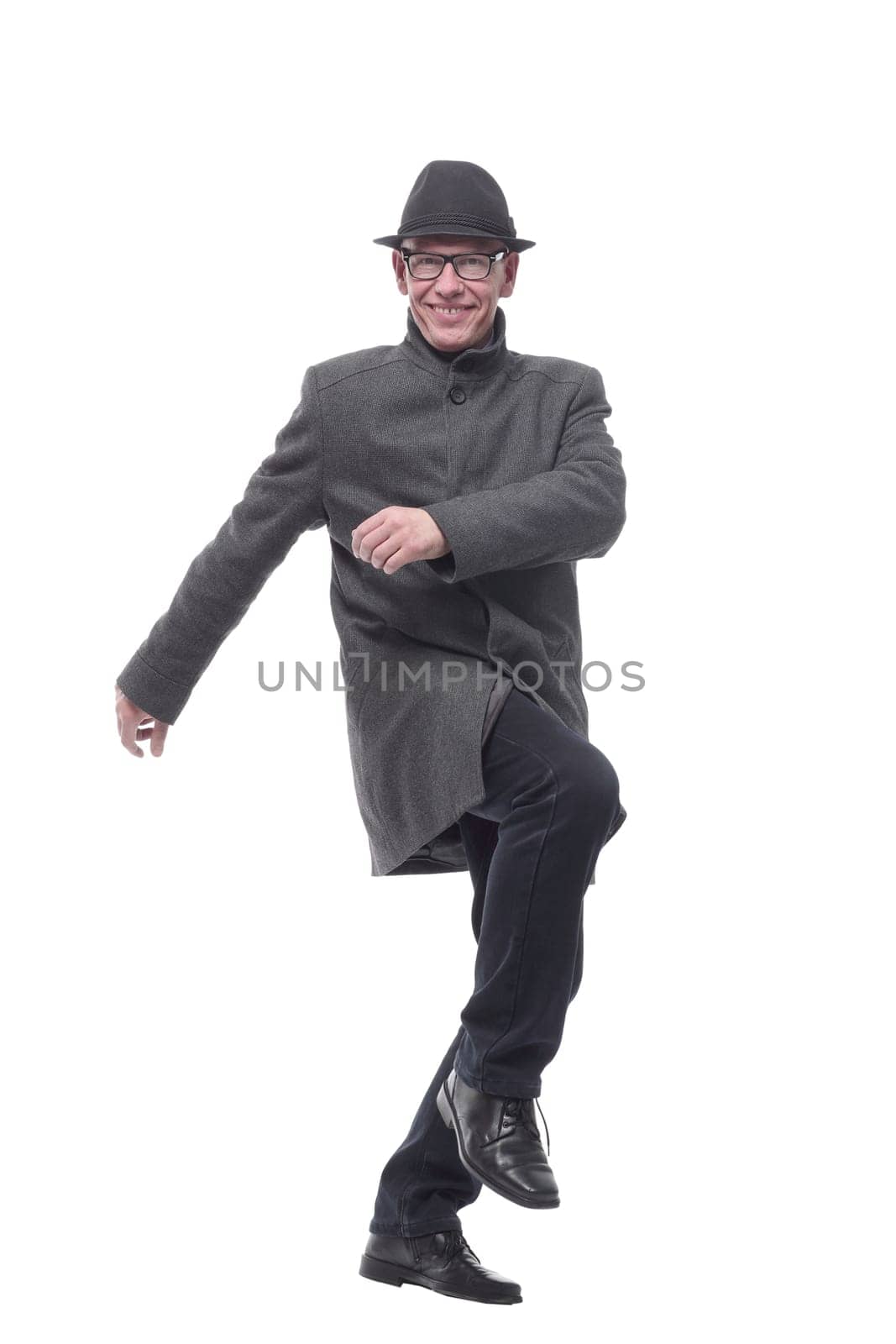 cheerful man in a hat and autumn coat striding forward . isolated on a white background