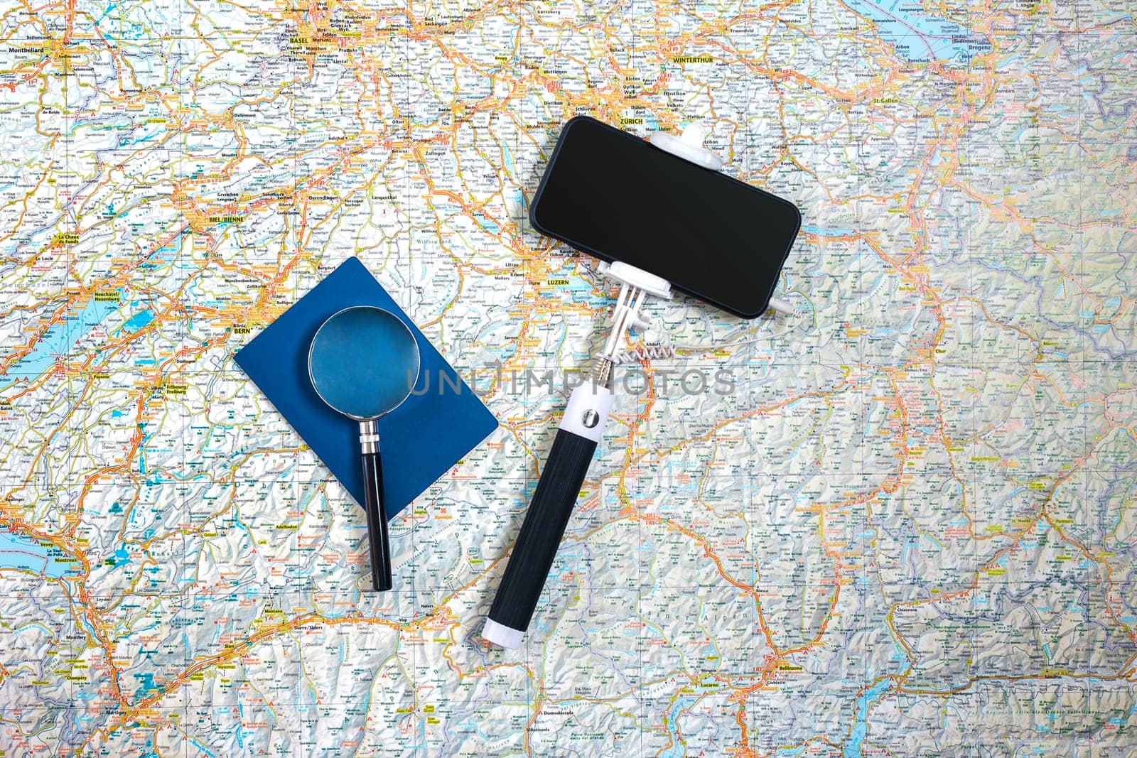 Travel accessories set on the map background: smart, passport and selfish stick. Top view point. Flat lay. Still life. Copy space