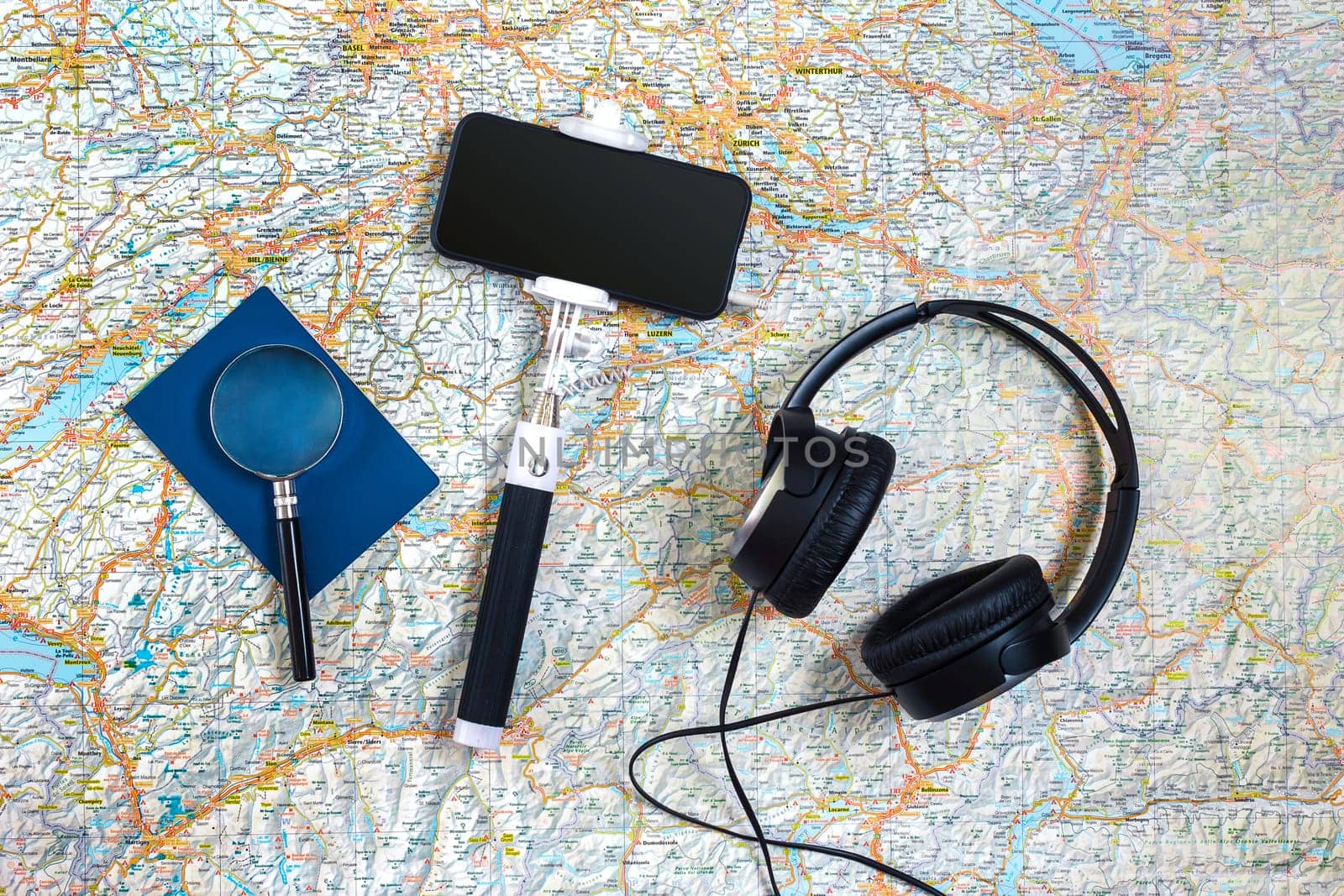 Travel accessories set on the map background: smart, headphones, passport and selfish stick. Top view point. Flat lay. Still life. Copy space
