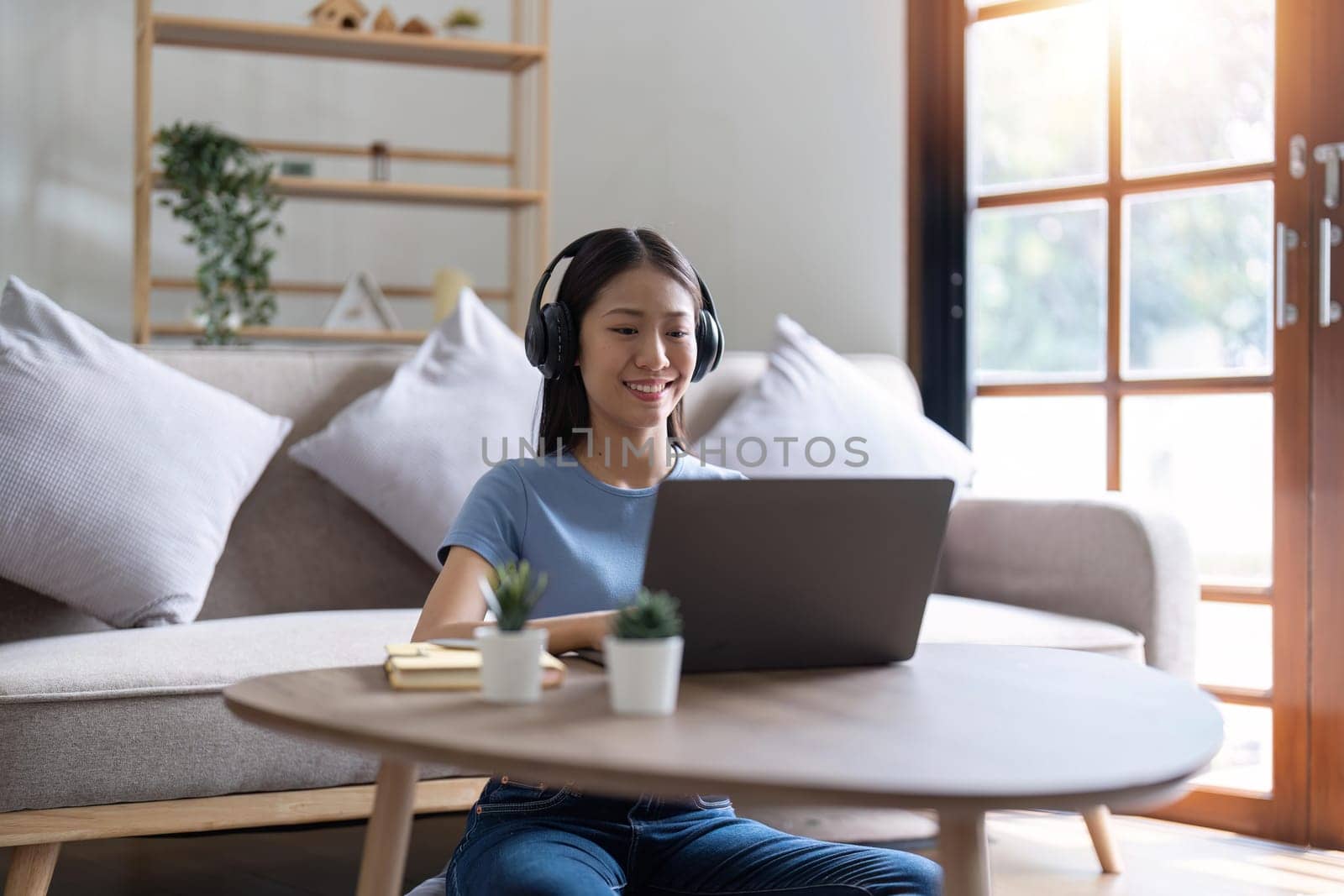 Young business freelance Asian woman working on laptop checking social media while sit on the sofa when relax in living room at home. Lifestyle at house concept.