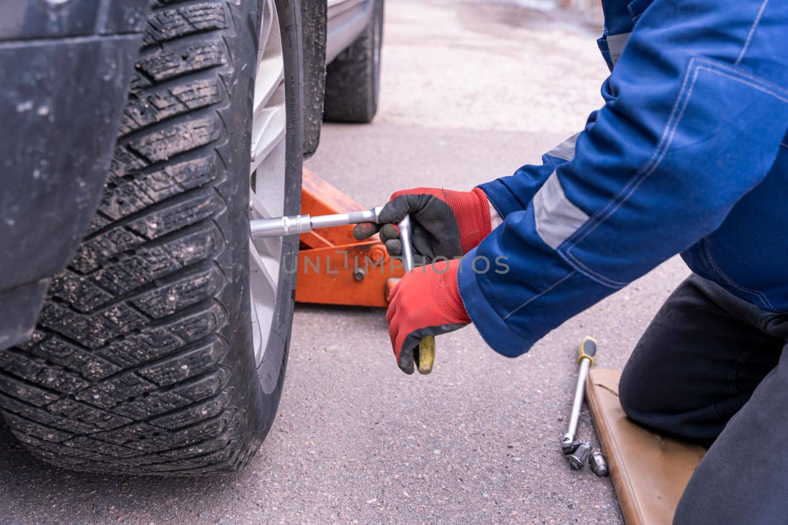 tightening of wheel nuts. The mechanic installs and screws the wheel on the car with a ratchet wrench. maintenance of motor vehicles. the concept of repair and maintenance. seasonal change of rubber. correct tightening torque of wheel nuts