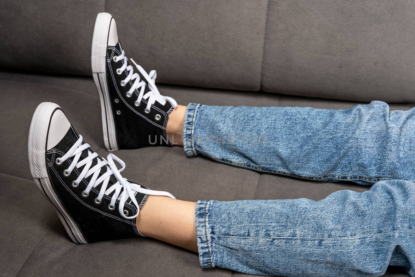 Teenager's feet in casual new sneakers on the sofa by audiznam2609
