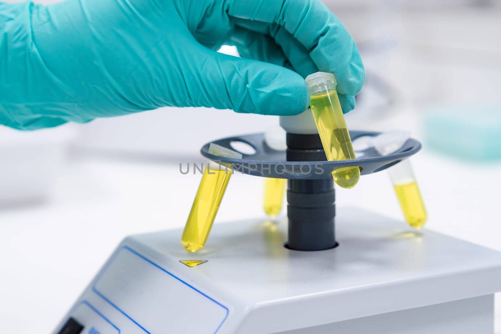 A scientist places a test tube into a microcentrifuge for the purpose of shaking or centrifuging samples intended for DNA analysis.