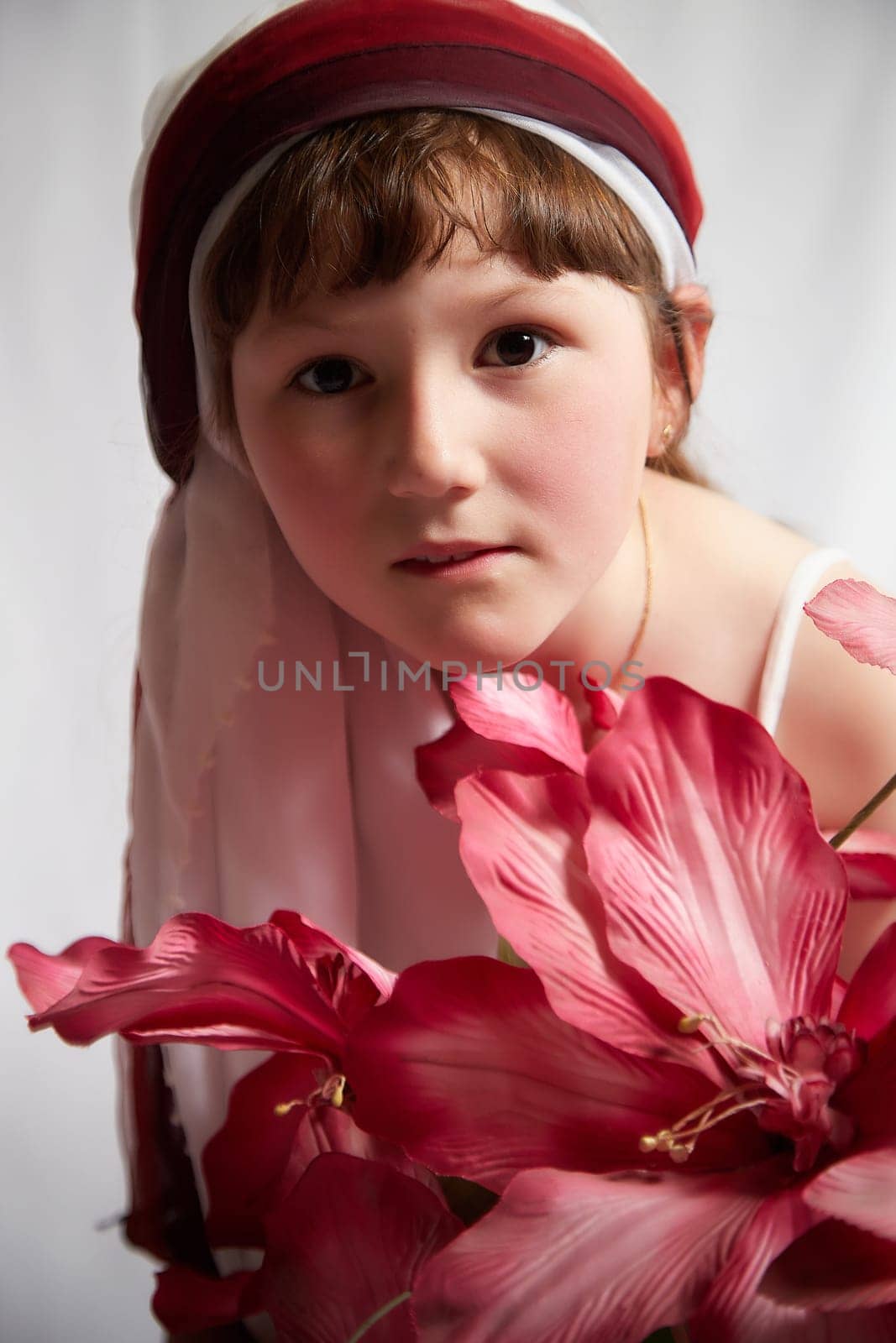 Portrait of Little girl in a stylized Tatar national costume with flowers on a white background in the studio. Photo shoot of funny young teenager who is not a professional model