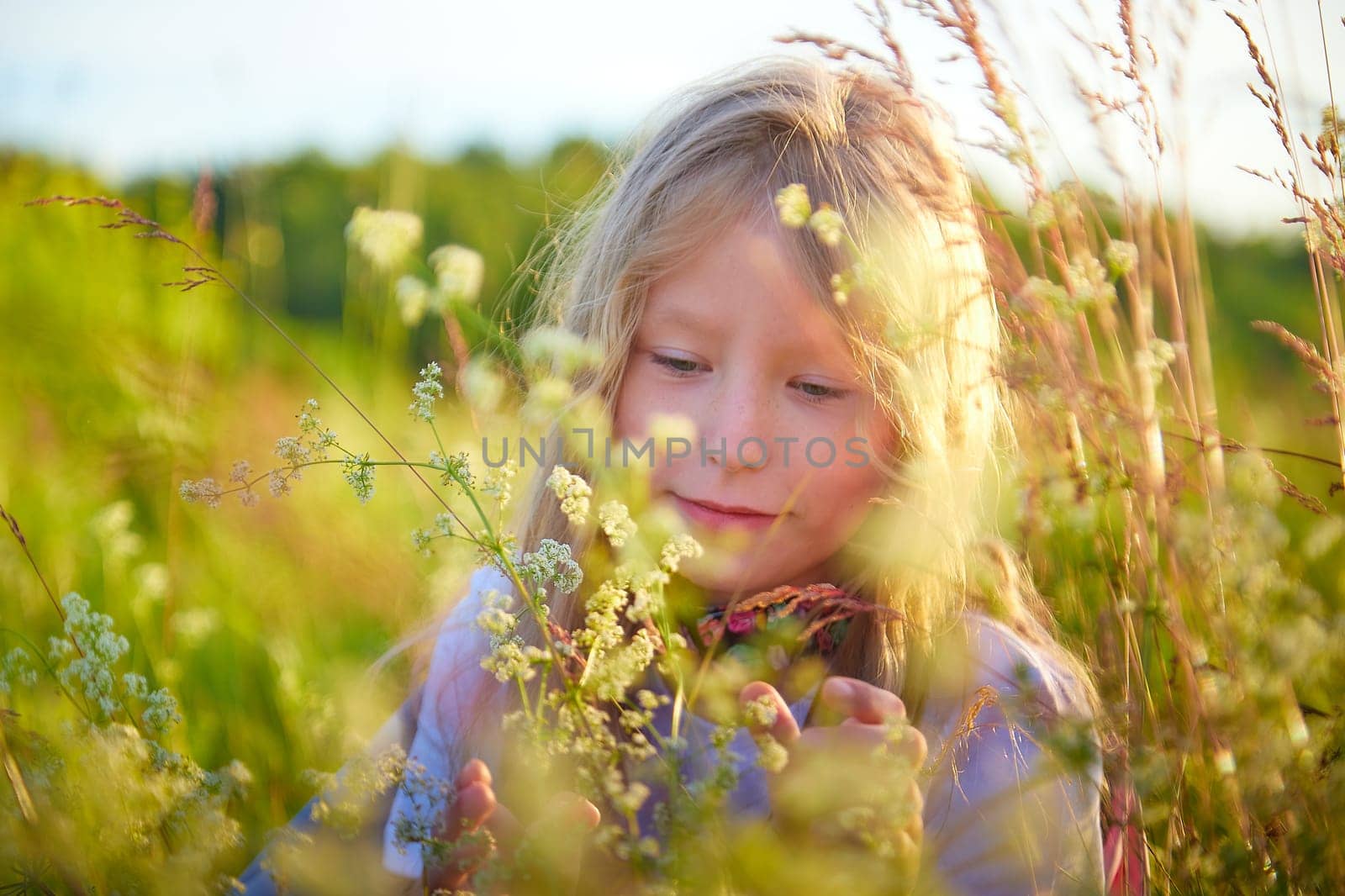 Portrait of pretty blonde girl having fun in a meadow on a natural landscape with grass and flowers on a sunny summer day. Portrait of a teenage child in summer or spring outdoors on field by keleny