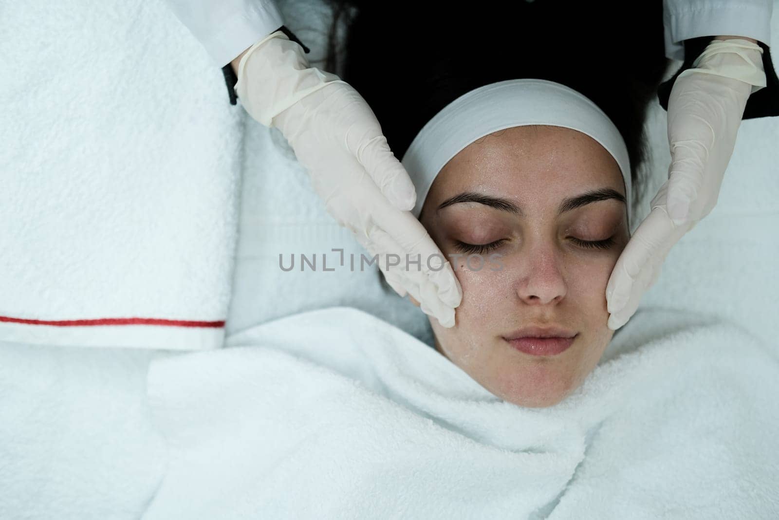 Cosmetologist cleaning woman's face before applying face treatments . Preparing patient's skin before treatment.