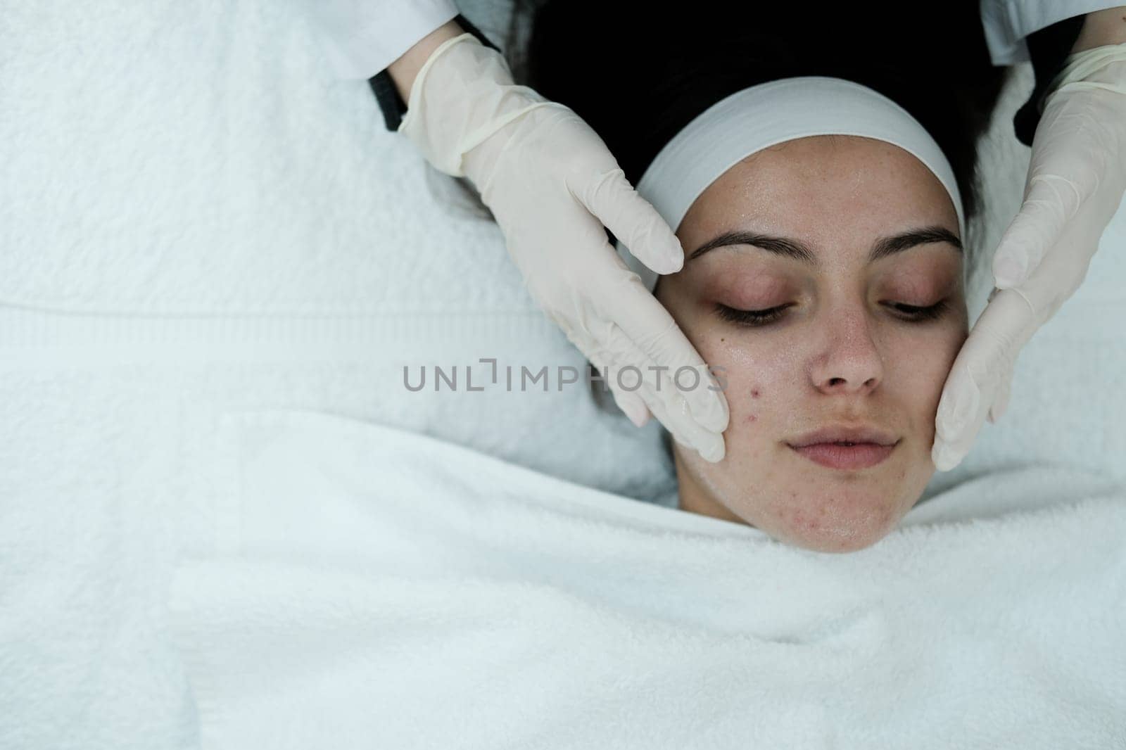 Cosmetologist cleaning woman's face before applying face treatments . Preparing patient's skin before treatment.