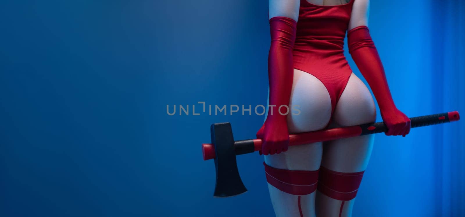Sexy buttocks of a girl in red bodysuit with an axe on a uniform blue background Copypasta