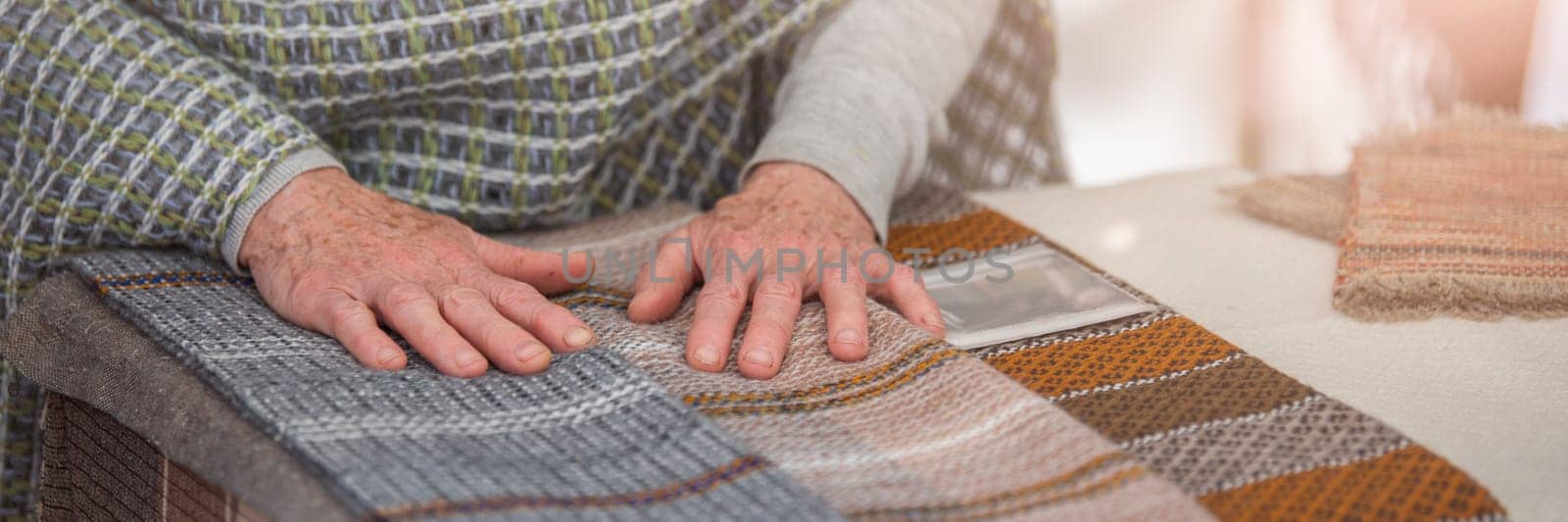 An elderly woman sells knitted items of her own production. Small business concept. by SERSOL