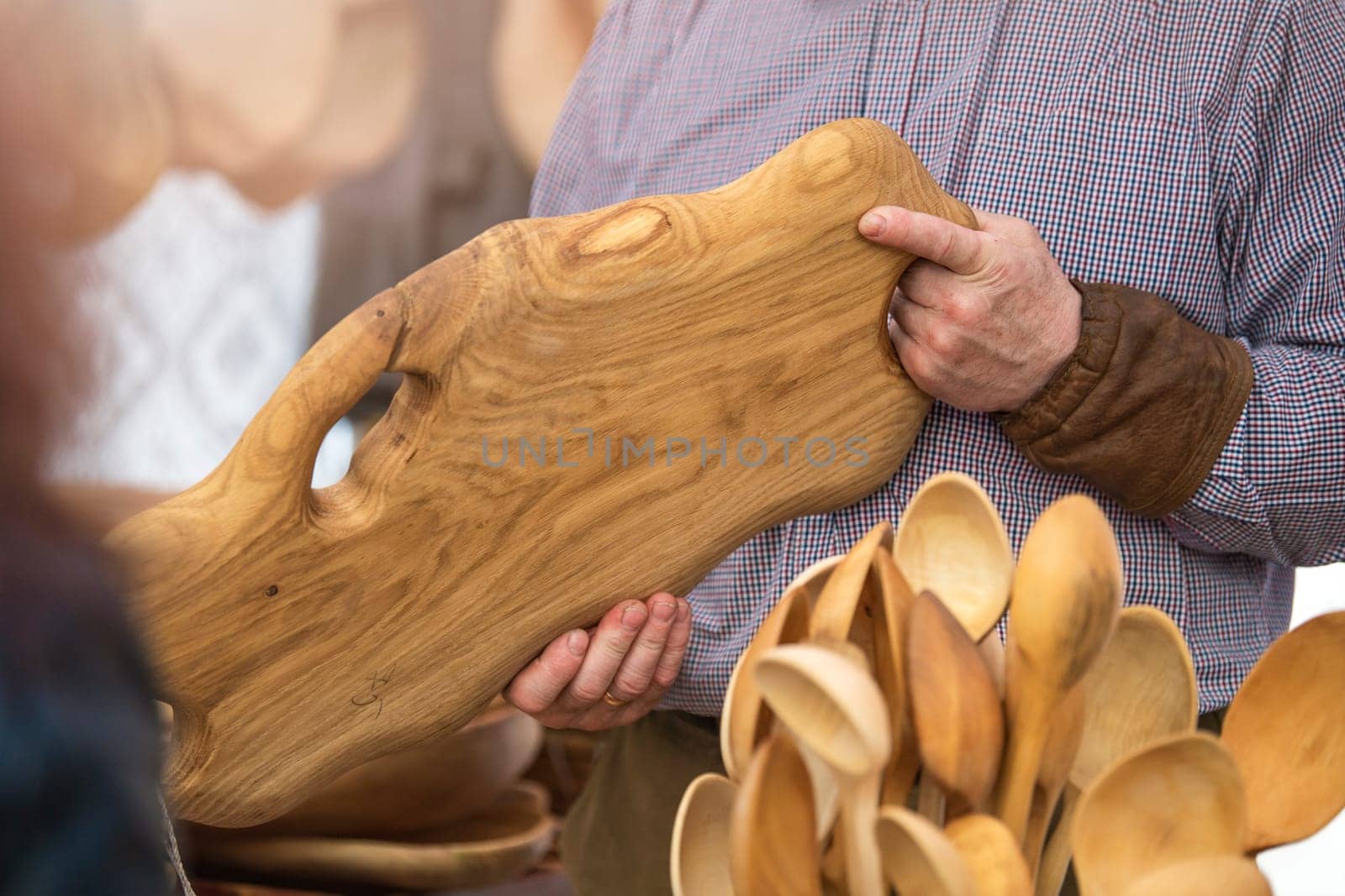 Production of wooden products in the concept of small business. Carpenter holding a rare wood tray in a carpentry workshop. Manufacture and sale of wooden furniture. High quality photo