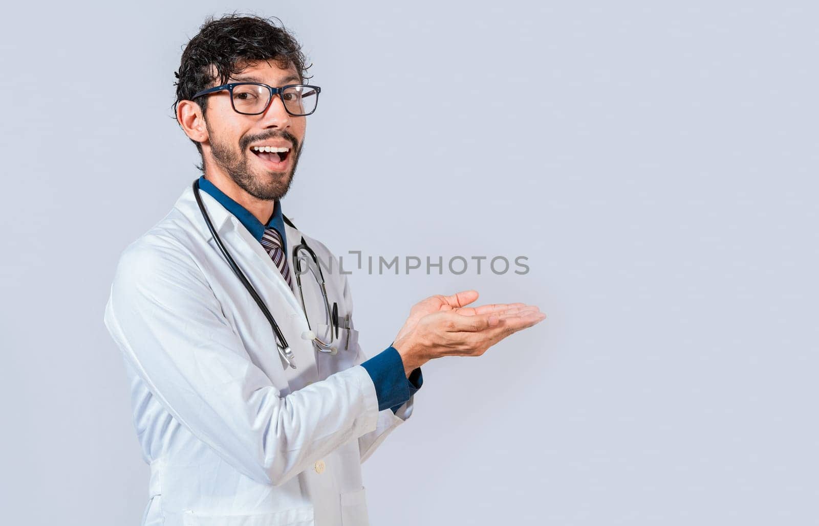 Smiling doctor showing something with his palms. Young doctor presenting something with palms isolated, Handsome doctor showing an advertisement with his palms