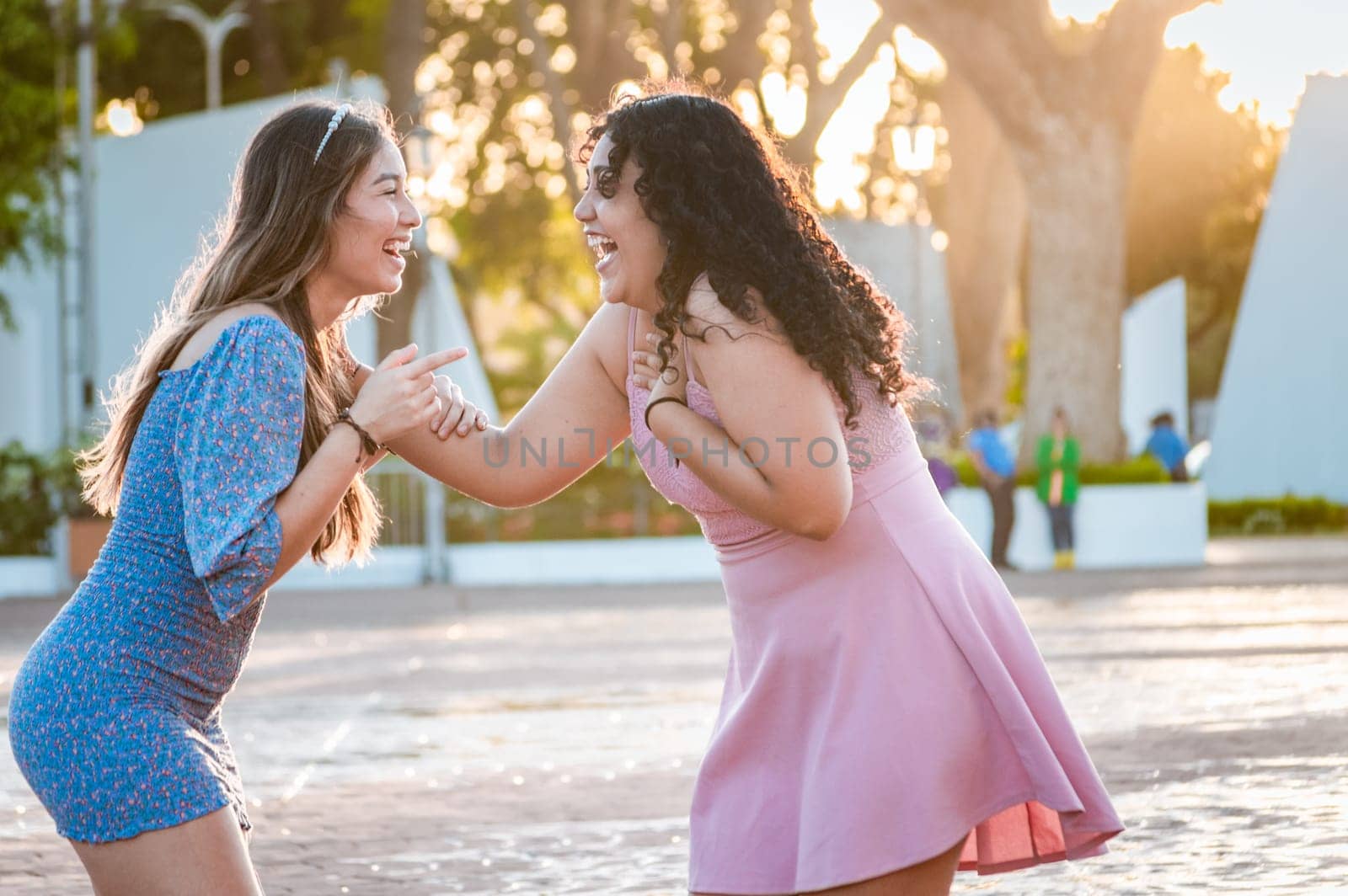 Happy female friends laughing in the street. Concept of happy female friends chatting in the street, Two happy girls laughing in the street by isaiphoto