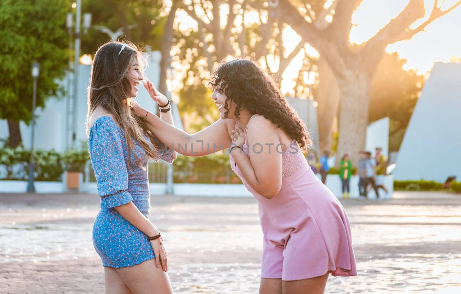 Two happy girls laughing in the street. Happy female friends laughing in the street. Concept of happy female friends chatting in the street