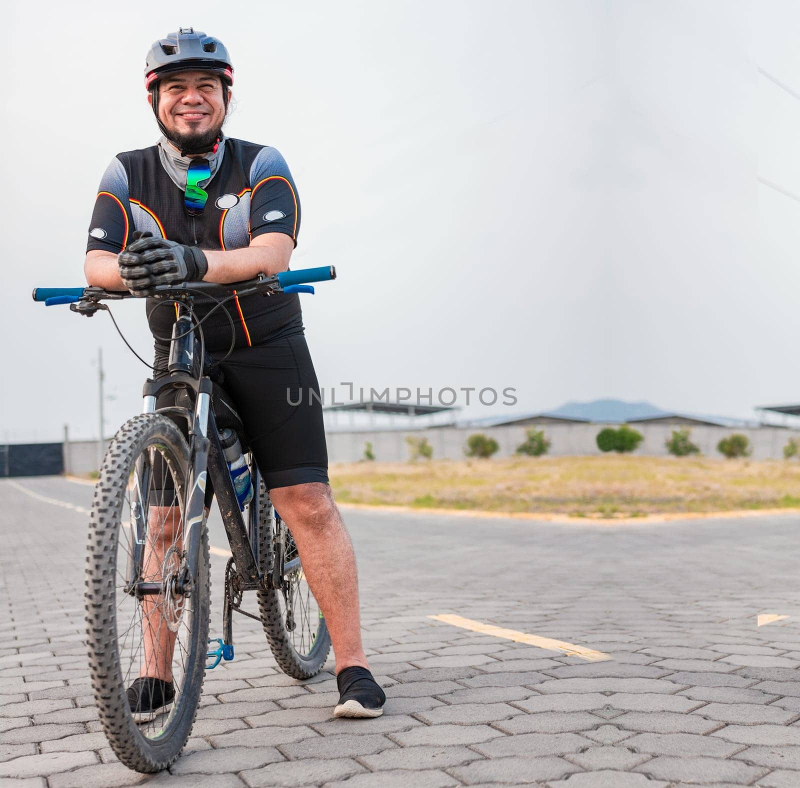 Portrait of cyclist on his bike looking at the camera with copy space. Chubby male cyclist in sportswear riding a bicycle outdoors by isaiphoto