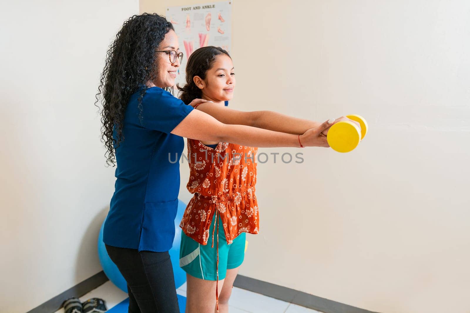 Rehabilitation physiotherapy in fitness ball. Physiotherapist helping patient with dumbbell sitting on rehabilitation ball by isaiphoto