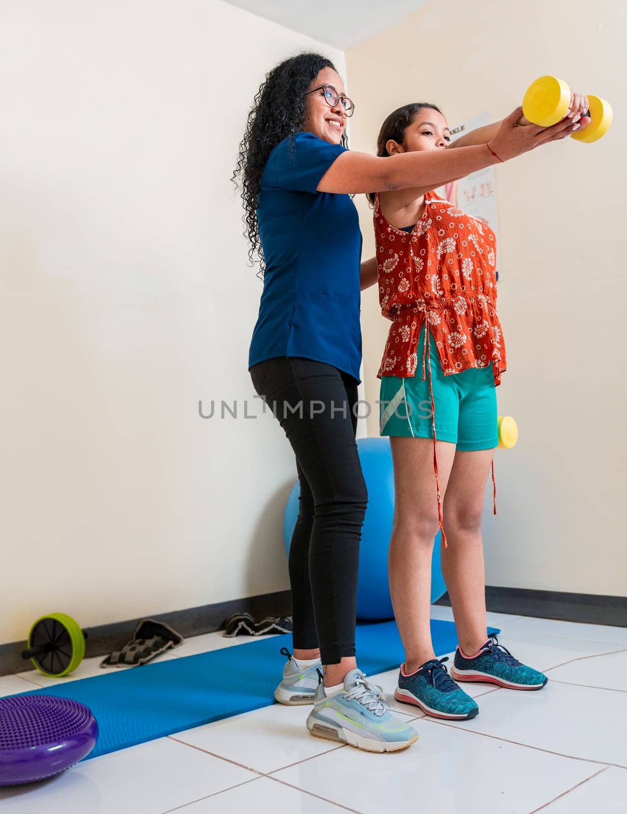 Rehabilitation physiotherapy with dumbbells. Physiotherapist helping patient with dumbbells on rehabilitation ball by isaiphoto