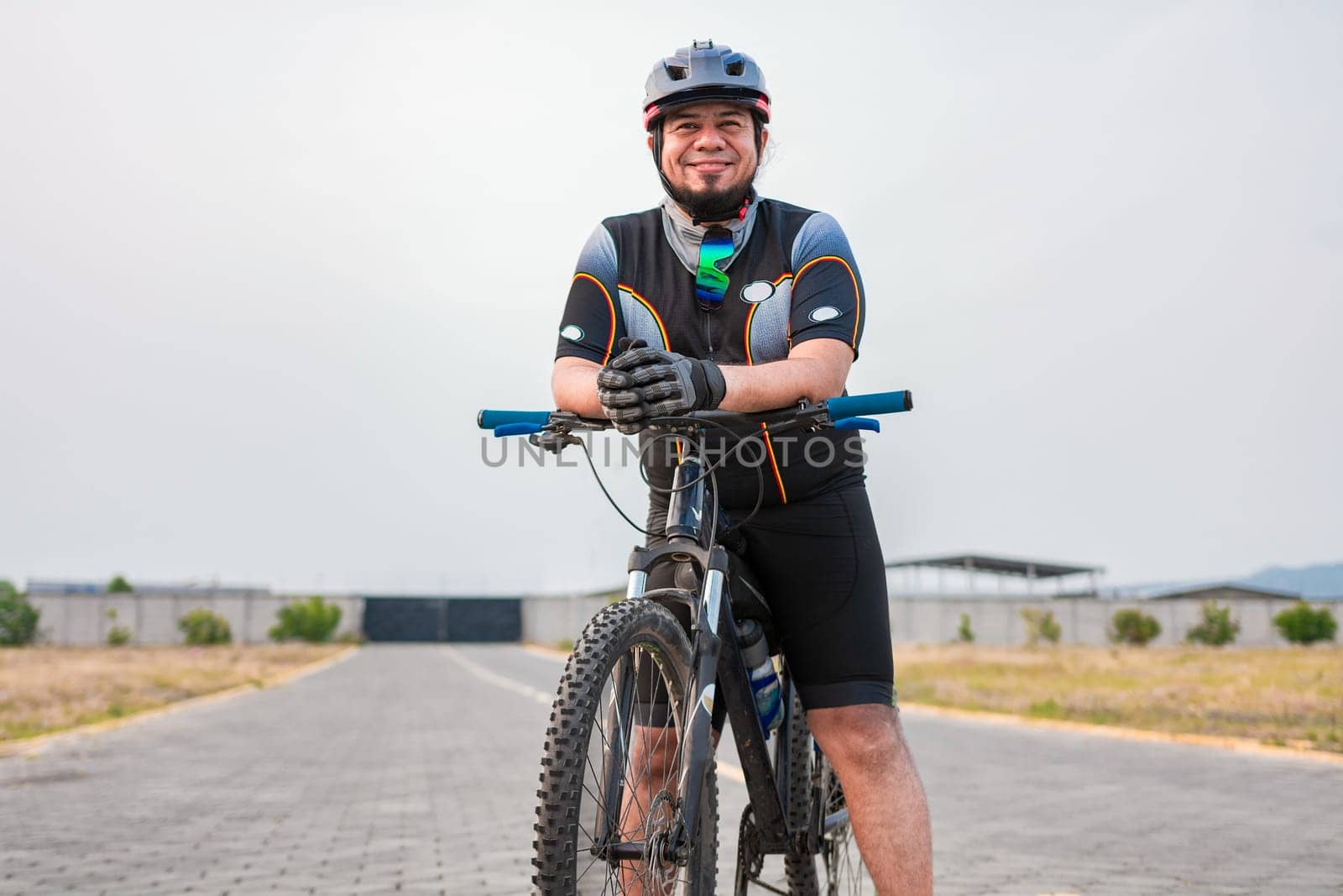 Smiling cyclist on his bike in sports outfit. Chubby male cyclist in sportswear riding a bicycle outdoors