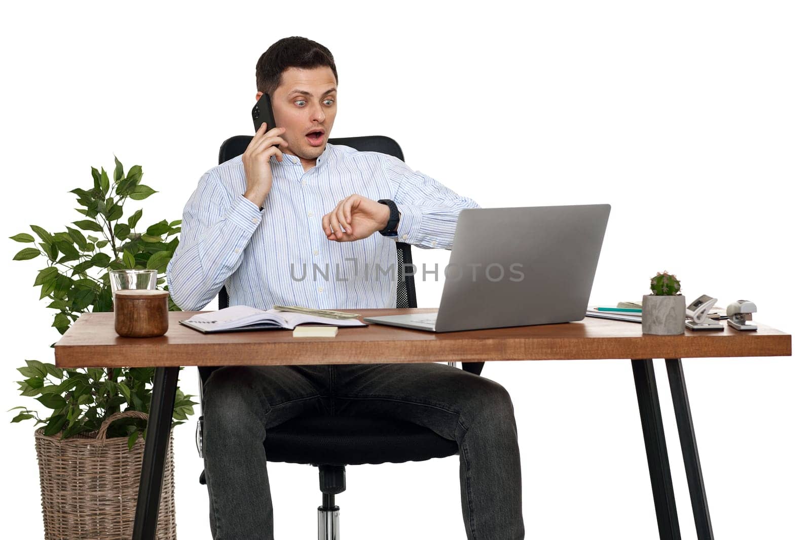 surprised businessman looking at watch while working with laptop and having phone conversation with client