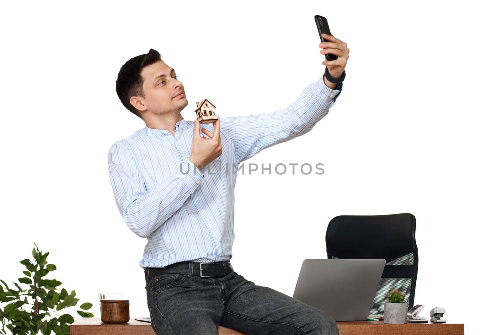 caucasian businessman holding toy house and taking selfie in the office. real estate insurance