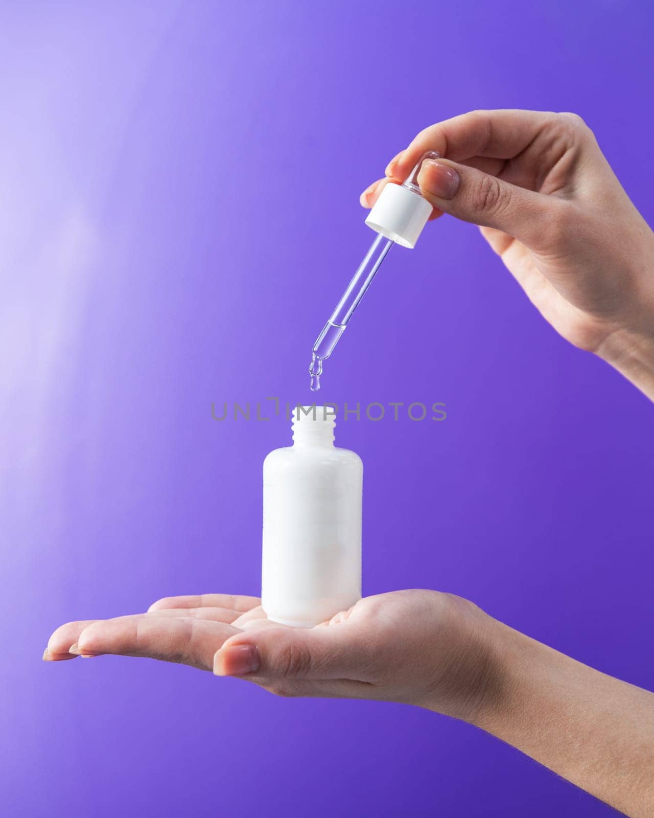 Women's hands hold pipette with cosmetic serum on lilac background,