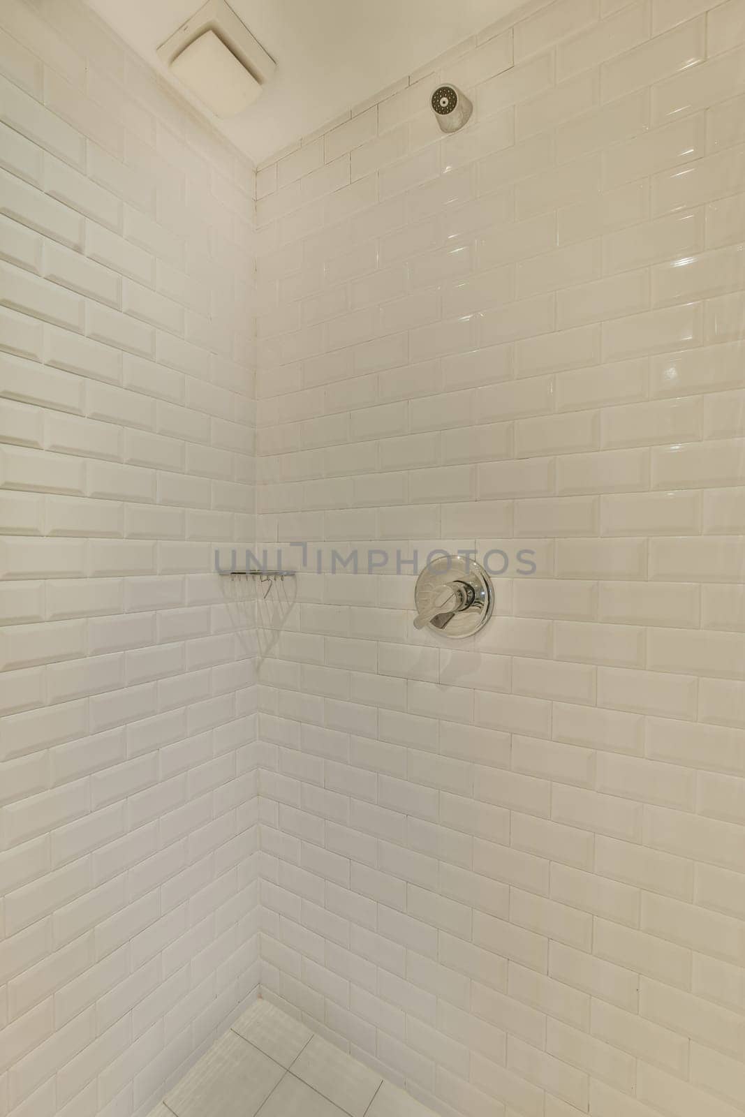 a white tiled shower in a small white bathroom by casamedia