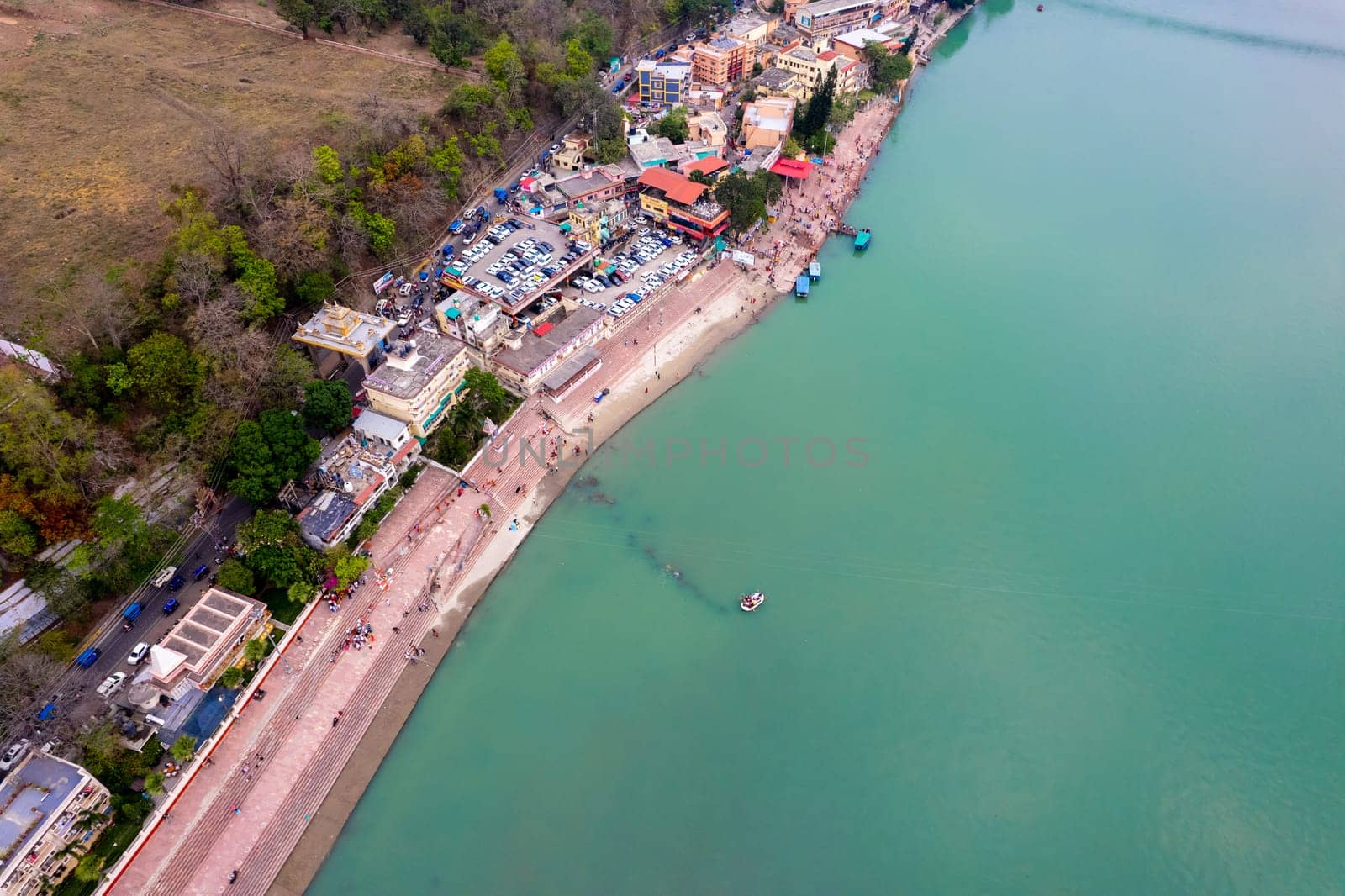 aerial drone shot of blue water of river ganga stretching into distance with steps stairs on the ghat bank of the river with temple and houses by Shalinimathur
