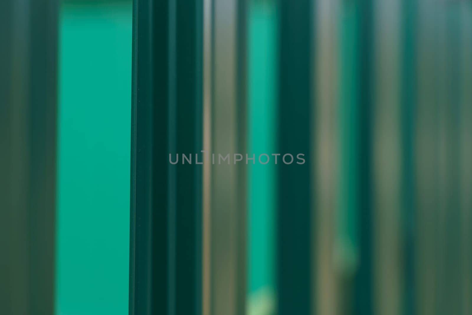 Green profiled fence, side view, close up. Abstraction and texture.