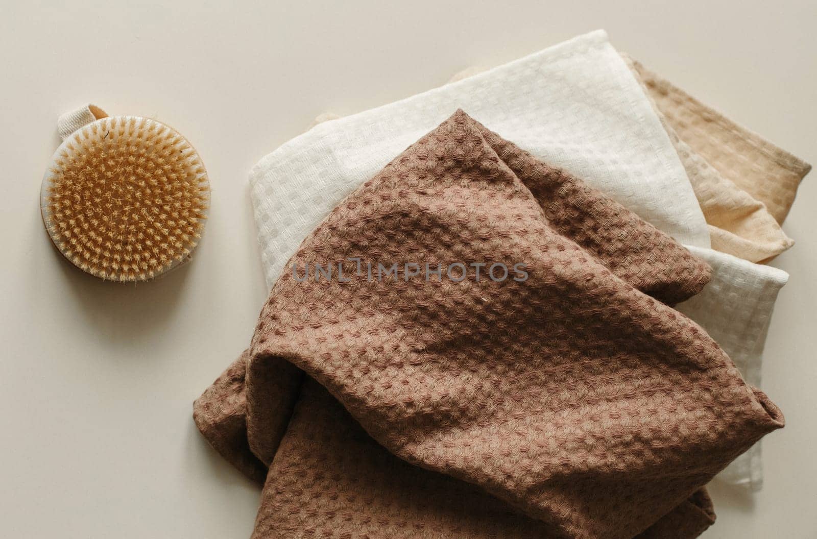 Towels and a washcloth brush lie on a beige surface.