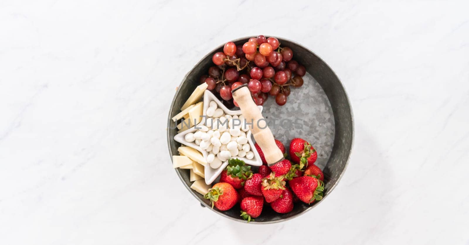 Flat lay. Building July 4th charcuterie board on a two-tiered serving metal stand.