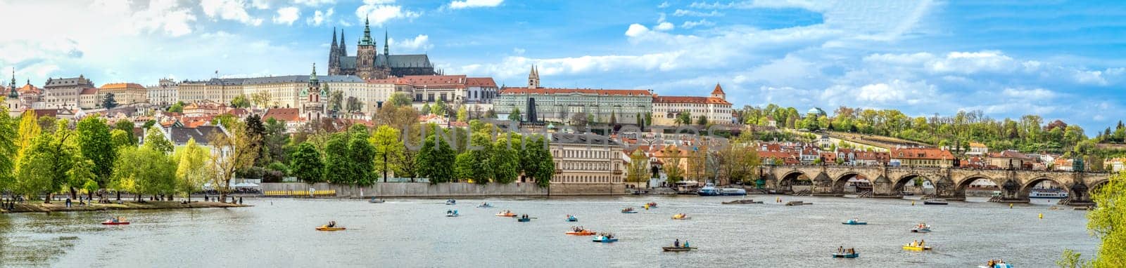 A panoramic view of Prague, the capital of the Czech Republic. View of Prague Castle and Charles Bridge. Summer time, people swim on catamarans. banner by Edophoto