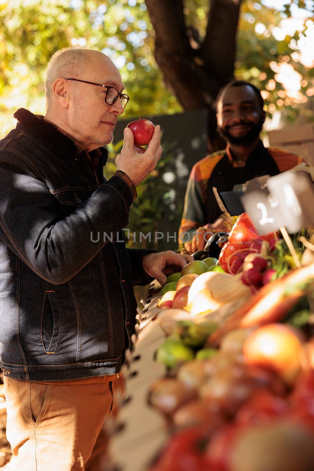 Retired man enjoying smell of fresh natural apples at farmers market by DCStudio