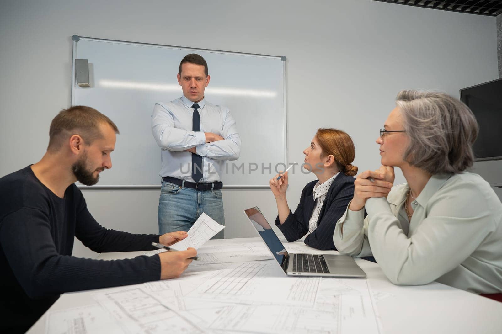 Caucasian man leading a presentation to colleagues at a white board